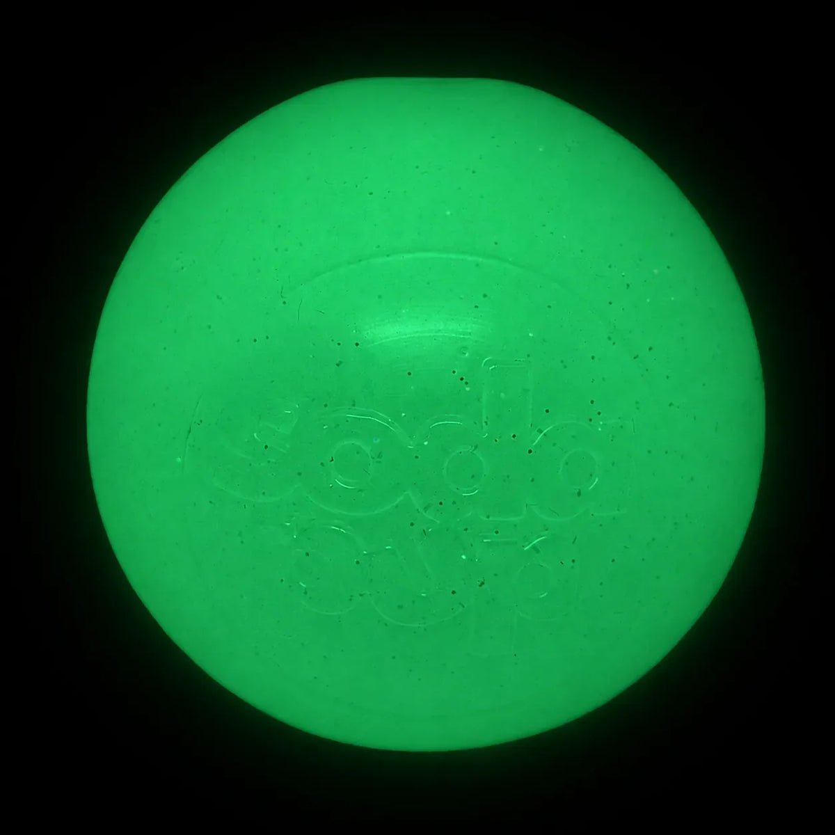 SodaPup Glitter Ball in glow in the dark, glowing bright green in a dark room