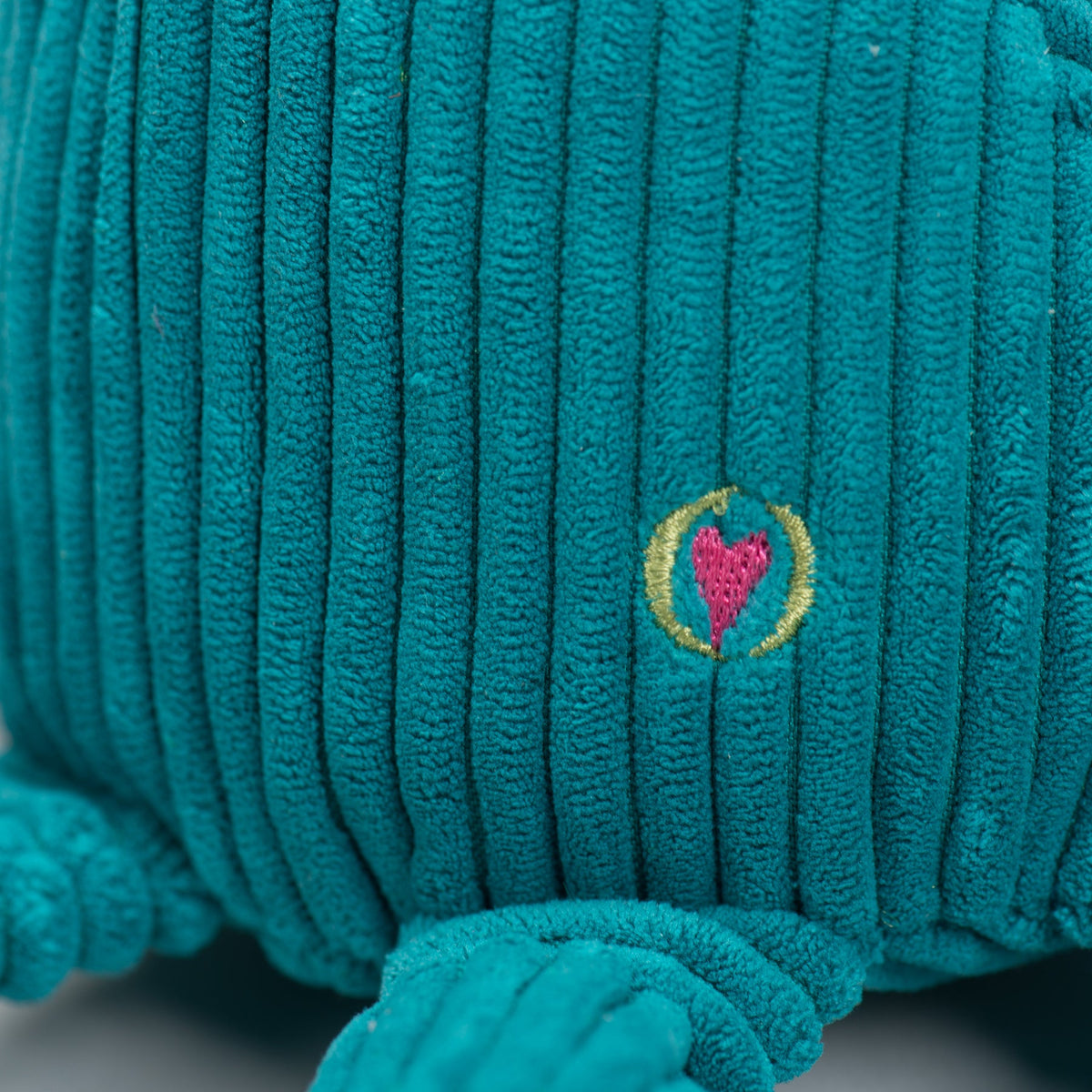 Octavie Octopus Knottie close-up of the embroidered pink heart logo on the teal Small