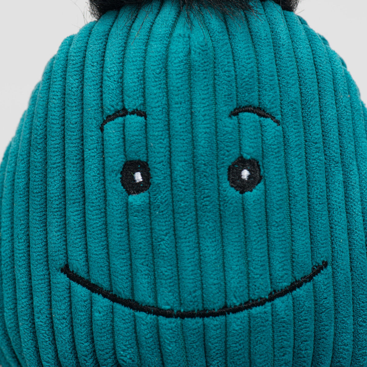 Octavie Octopus Knottie close-up of the teal Small's stitched smile and eyes on corduroy