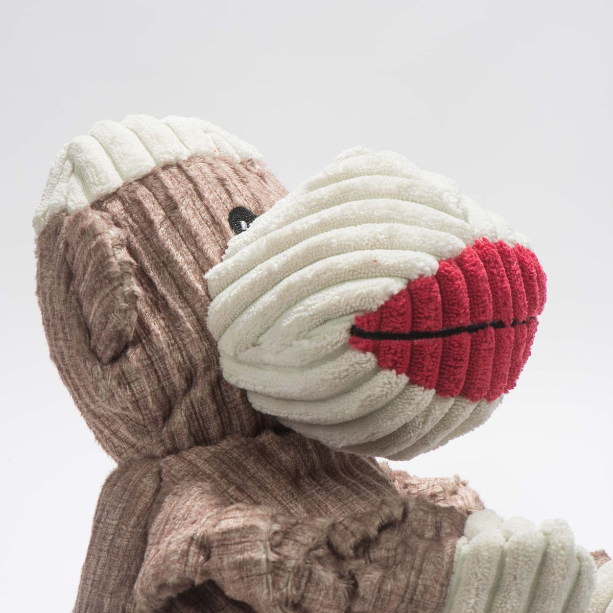 Stuey Sock Monkey Knottie close-up in profile, cream corduroy muzzle with red lips and a black eye