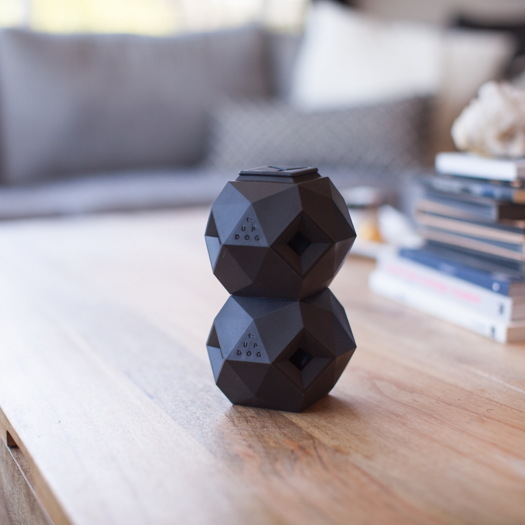 Up Dog Odin Treat Puzzle Balls in slate grey, two stacked on a wooden coffee table in a living room