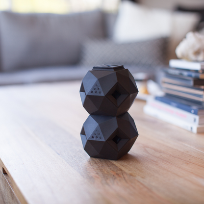 Up Dog Odin Treat Puzzle Balls in slate grey, two stacked on a wooden coffee table in a living room
