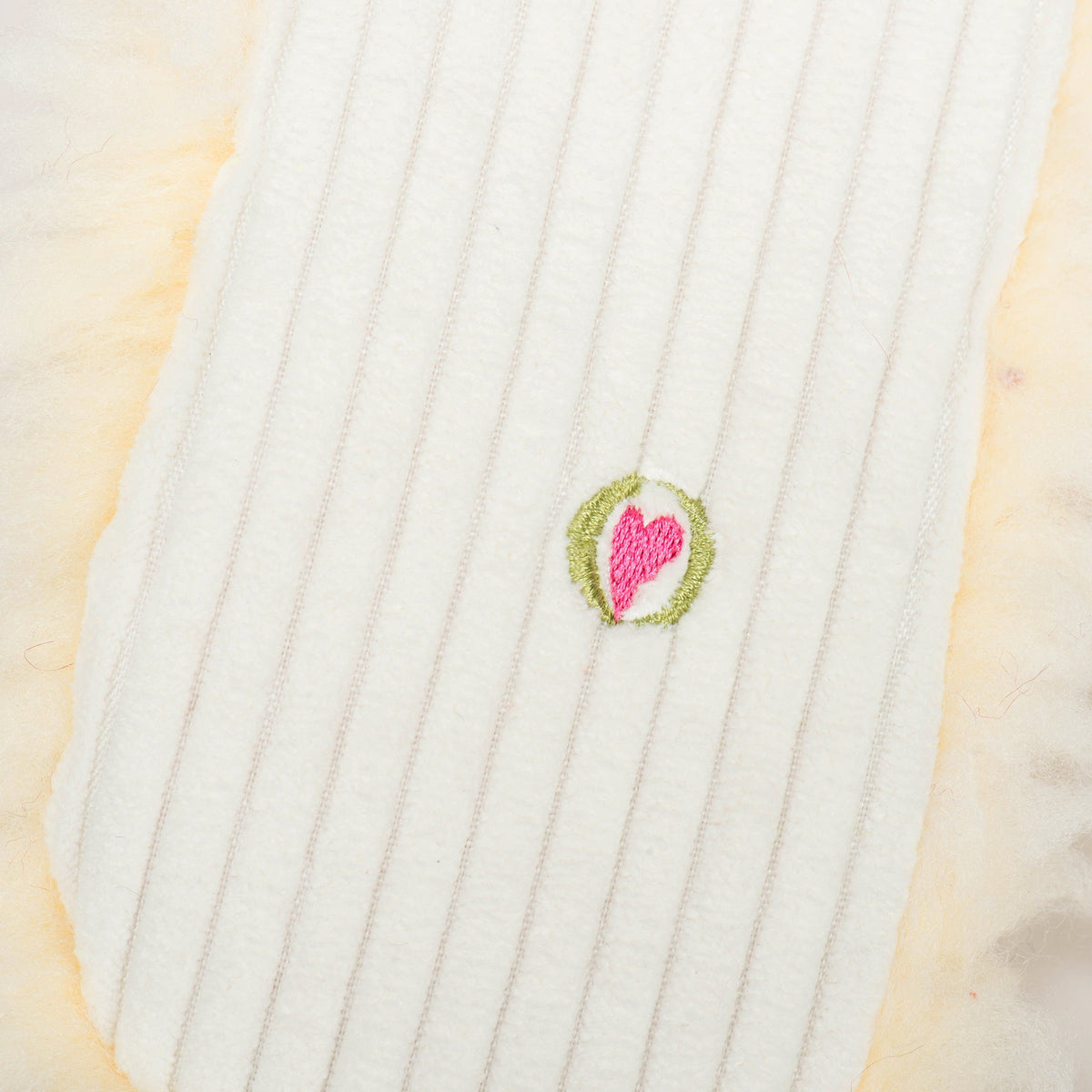 Louise Lamb plush close-up of the small embroidered pink heart logo on her corduroy back