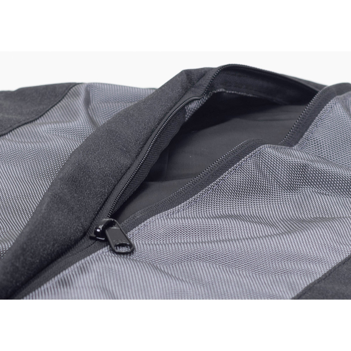 Round Bolstered Armor dog bed in charcoal, underside with the zipper partly open between non-skid strips