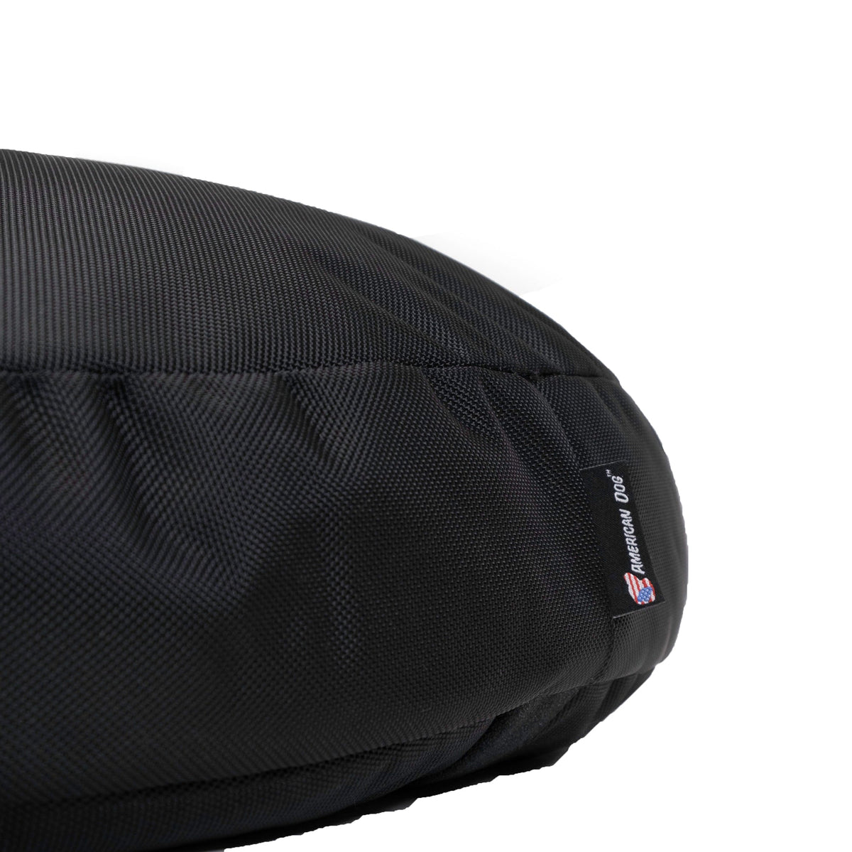 Close-up of the Round Armor dog bed's black ballistic nylon weave and American Dog label