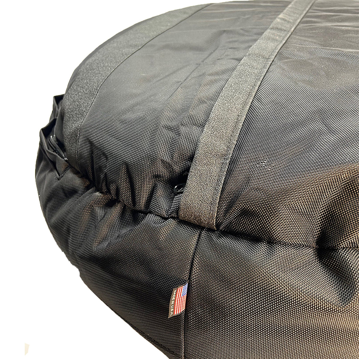 Round Bolstered Armor dog bed in black, underside close-up with non-skid strips, zipper and Made in USA flag tag