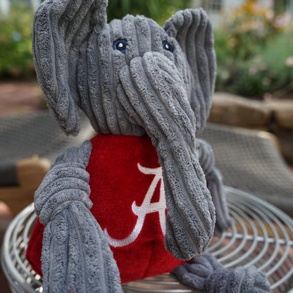 Big Al Knottie dog toy close-up on a round wire seat outdoors, long corduroy trunk and blue stitched eyes
