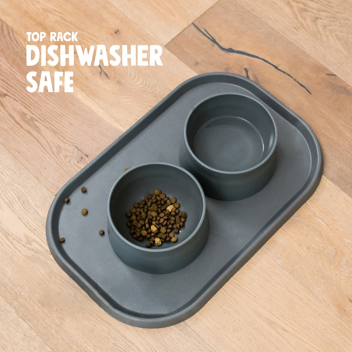 Non-Slip Placemat in sea fog gray with two matching bowls (sold separately) and a few kibble pieces on the mat