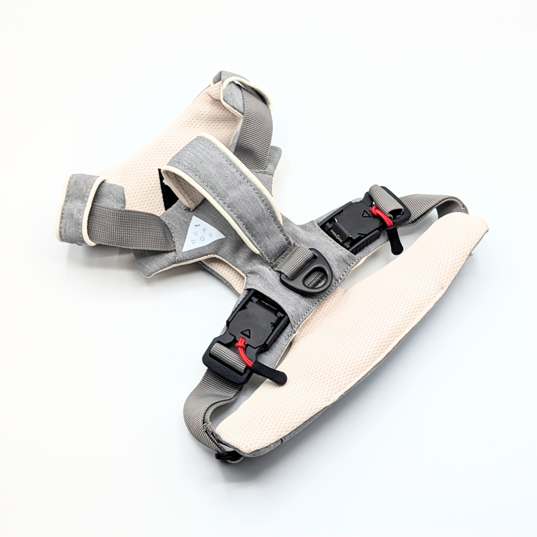 Up Dog harness folded at an angle, showing the two magnetic buckles with red pull tabs and the back clip