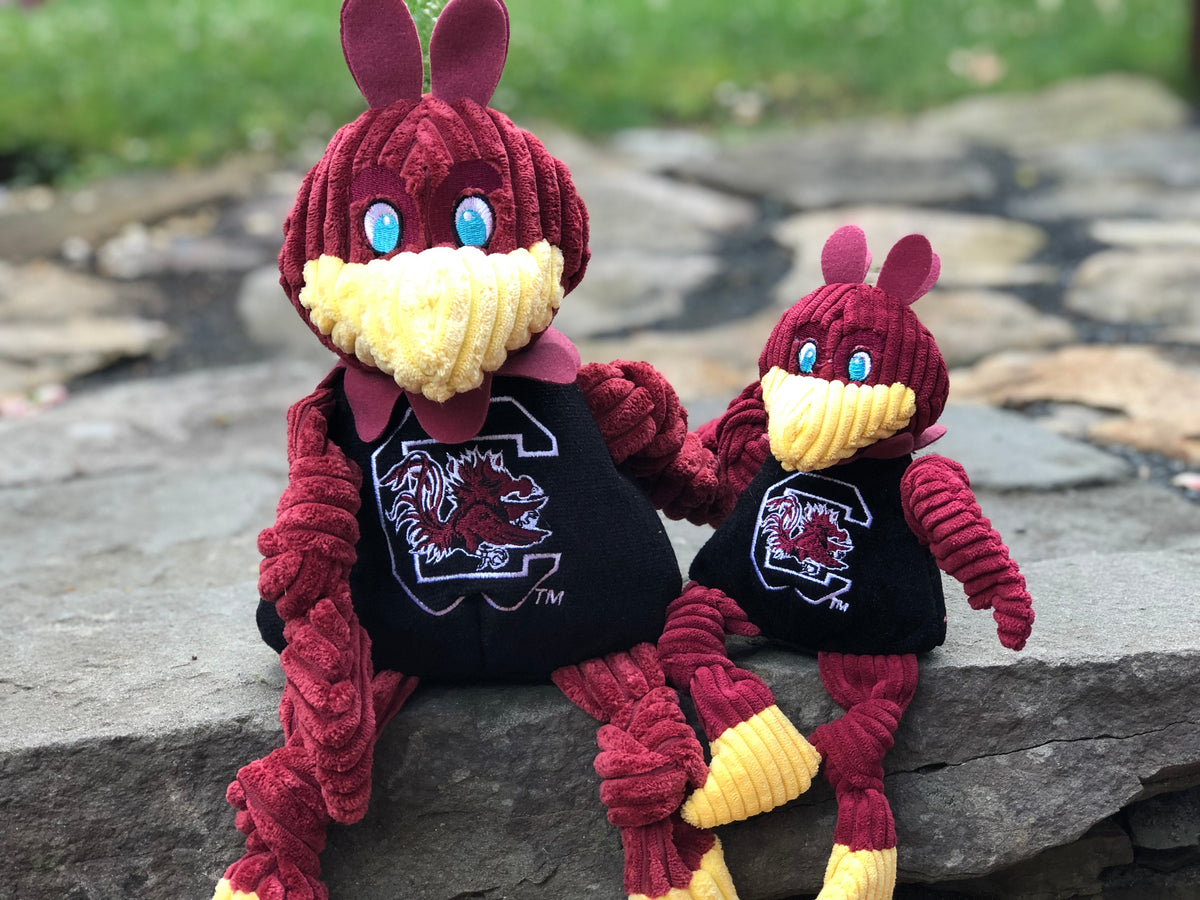 Cocky Knottie dog toy in two sizes sitting side by side on a stone ledge outdoors