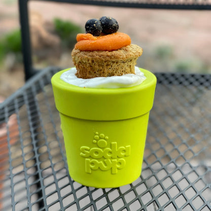 Flower Pot treat cup in green on a mesh patio table, filled with yogurt and topped with a muffin and blueberries