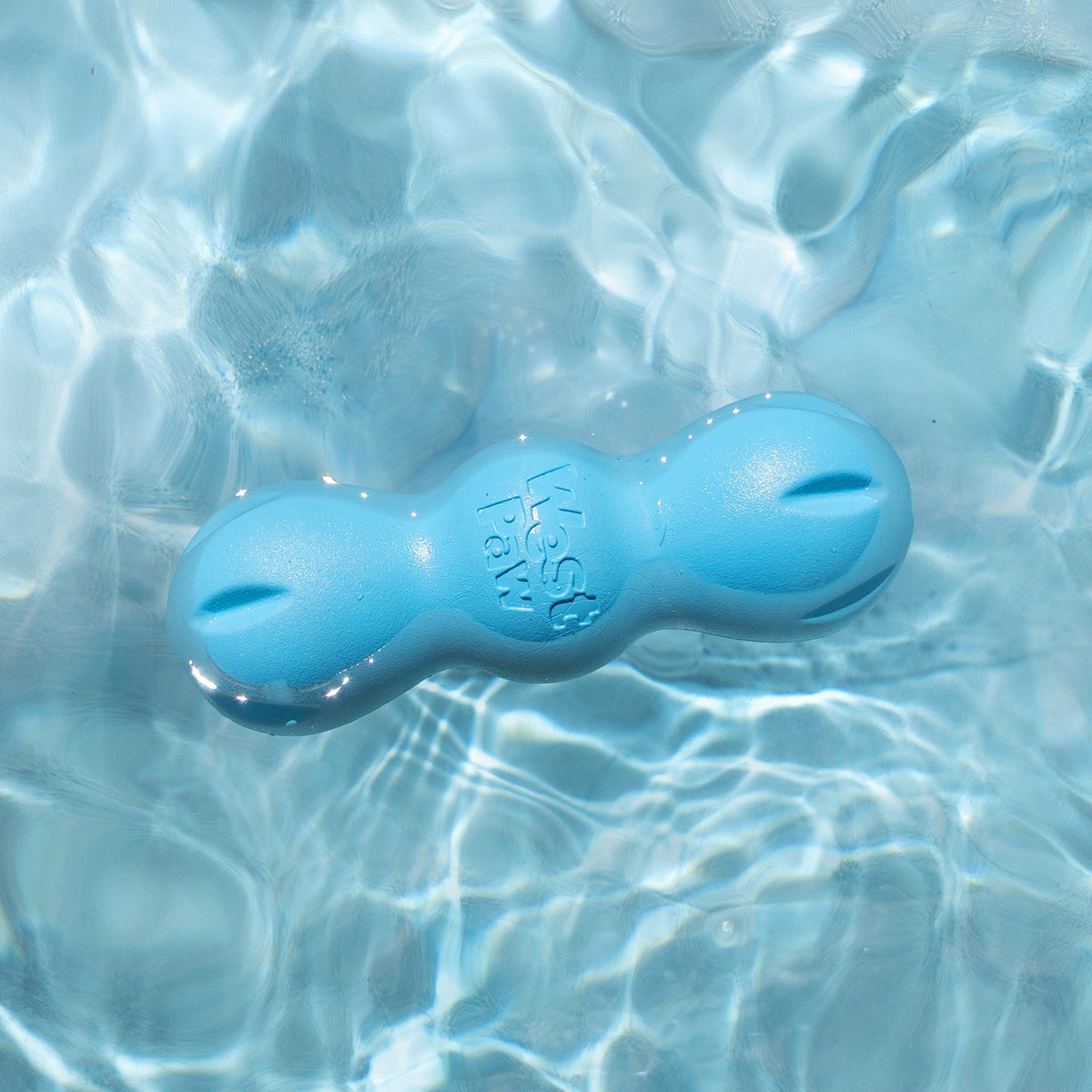 Rumpus chew toy in aqua blue floating on clear, rippling pool water