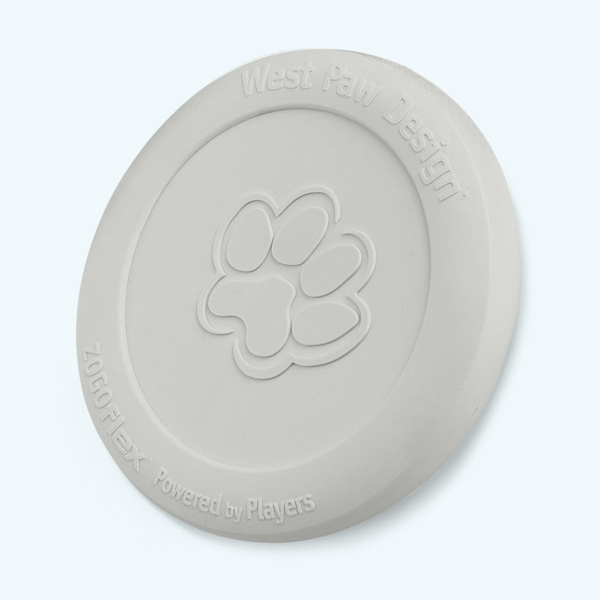 Glow in the dark West Paw Zisc flying disc, off-white in daylight, standing on its edge