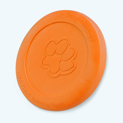 West Paw Zisc flying disc in tangerine orange, standing on its edge with the paw print facing forward