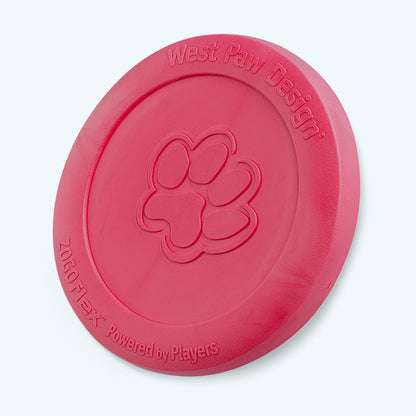 West Paw Zisc flying disc in ruby red, standing on its edge with the paw print facing forward