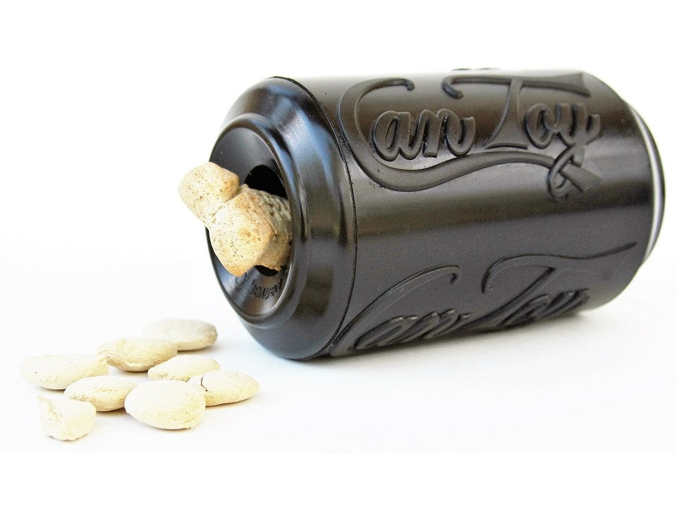 Black SodaPup Magnum Can Toy on its side with a bone biscuit wedged in the opening and treats beside it