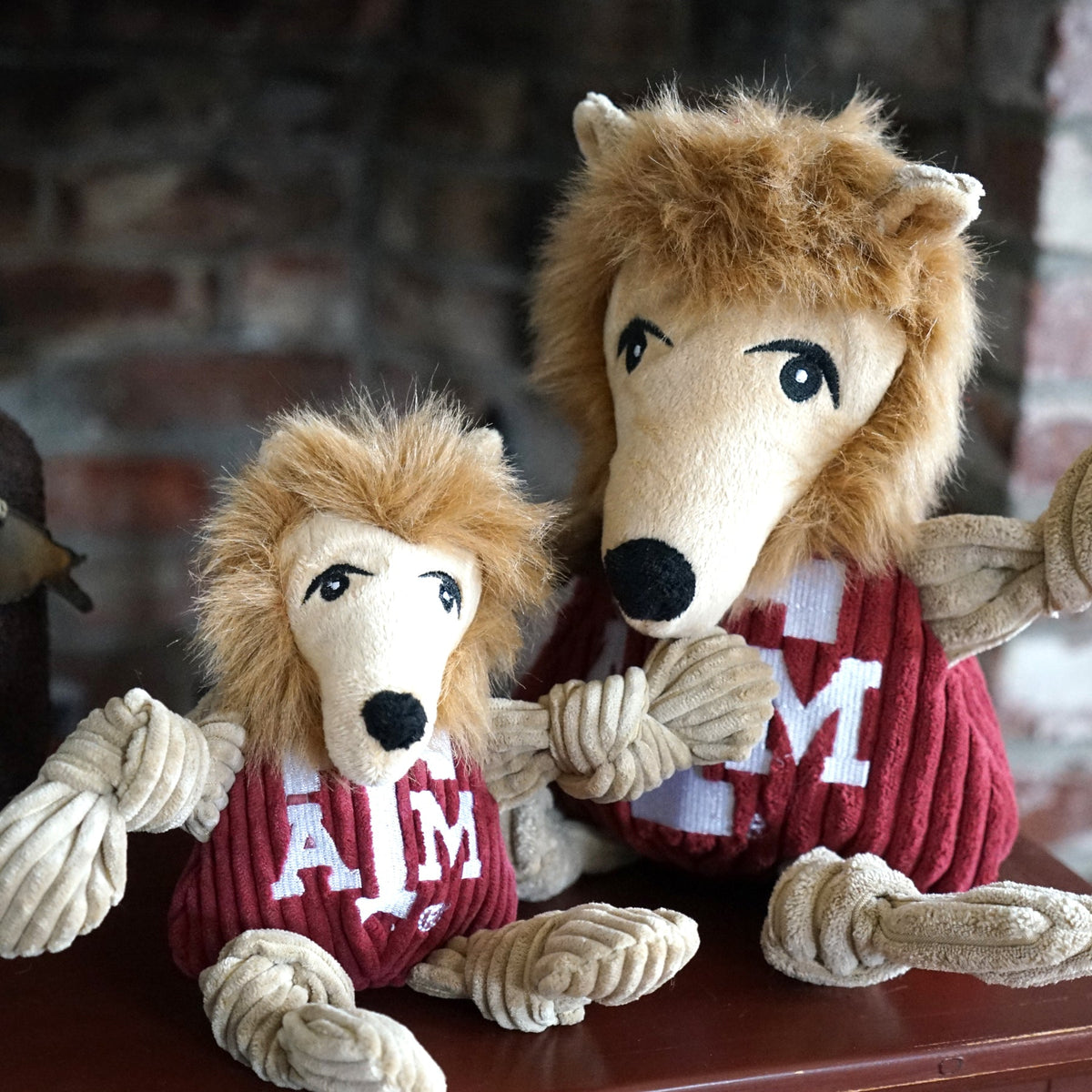 Reveille Knottie dog toy in two sizes sitting together on a wooden shelf by a brick wall