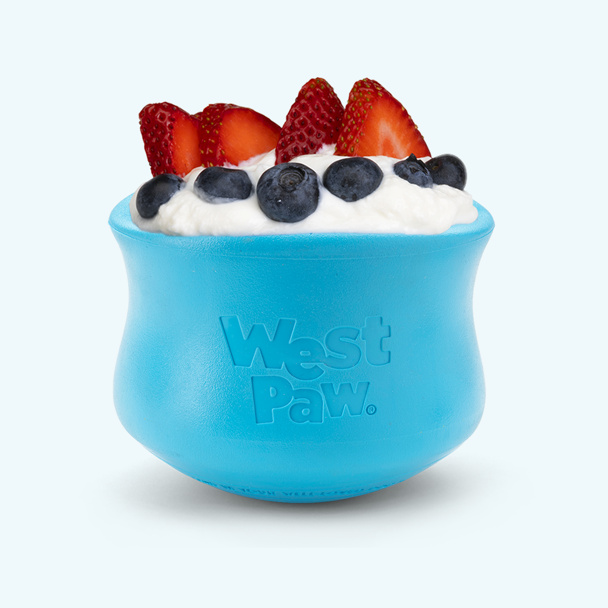 Aqua blue West Paw Toppl treat toy heaped with yogurt, sliced strawberries, and blueberries