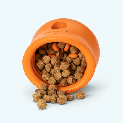 Tangerine West Paw Toppl tipped on its side and spilling kibble, showing the rubber nubs inside
