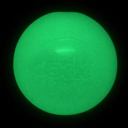SodaPup Glitter Ball in glow in the dark, glowing bright green in a dark room
